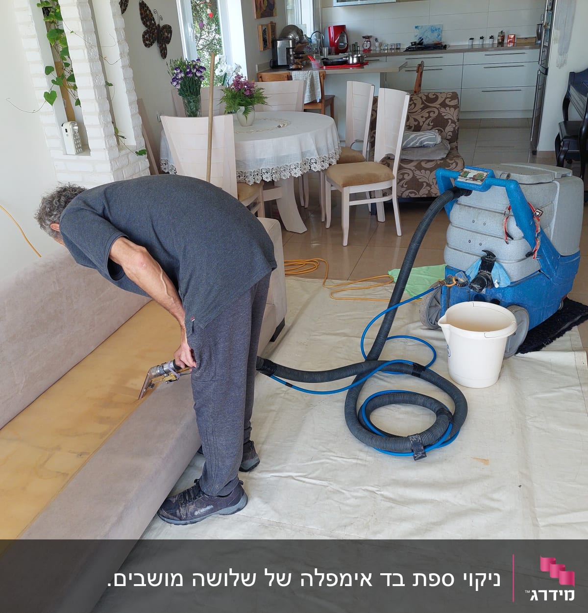 אדם מנקה ספה עם מכונת ניקוי מקצועית